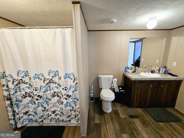 full bath featuring vanity, toilet, wood finished floors, and a textured ceiling