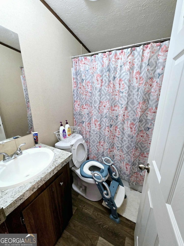 bathroom with vanity, wood finished floors, a textured ceiling, curtained shower, and toilet