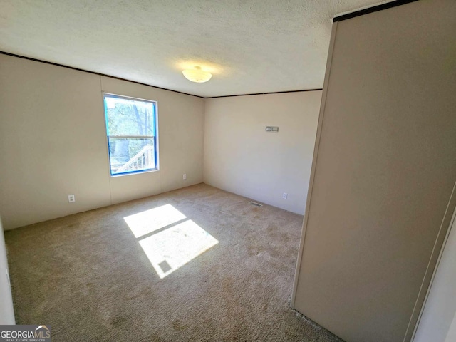 unfurnished room with visible vents, a textured ceiling, and carpet flooring