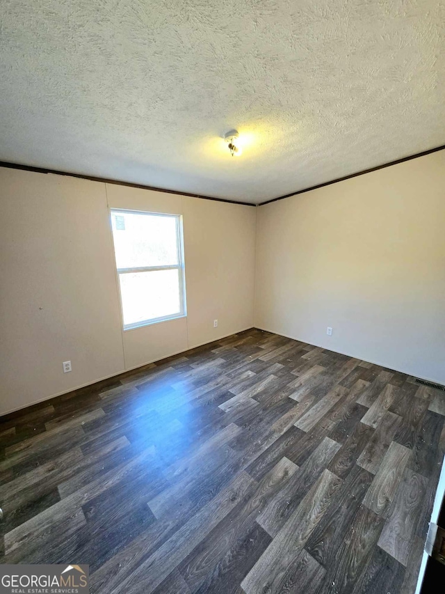 spare room featuring a textured ceiling, wood finished floors, and ornamental molding