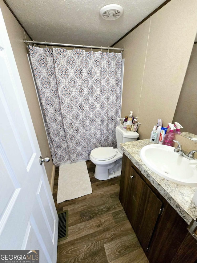 bathroom featuring vanity, wood finished floors, visible vents, and a textured ceiling