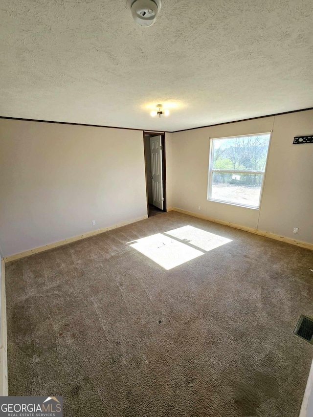 unfurnished room featuring visible vents, baseboards, a textured ceiling, and carpet flooring