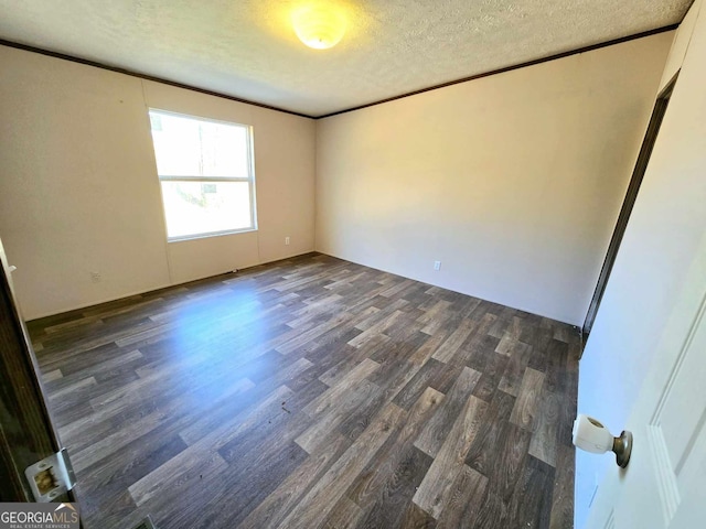 spare room with dark wood-type flooring, ornamental molding, and a textured ceiling