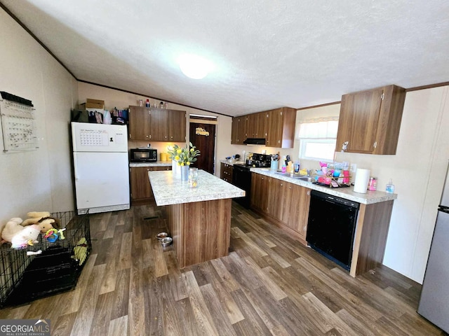 kitchen featuring dark wood-type flooring, black appliances, light countertops, and lofted ceiling