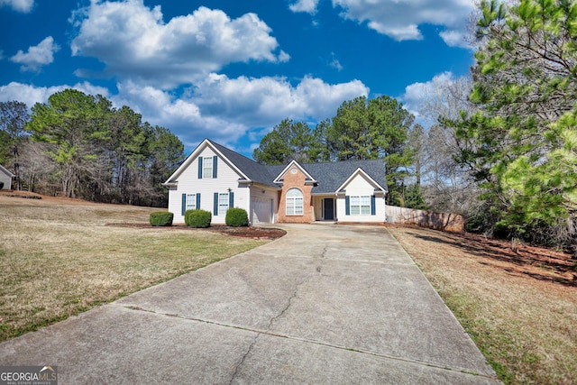 view of front of house with brick siding, a front lawn, driveway, and fence