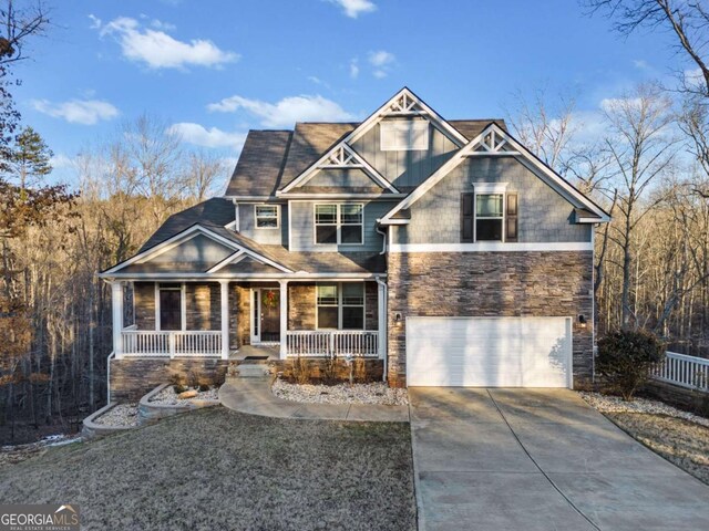 craftsman-style home featuring a garage, stone siding, covered porch, and concrete driveway