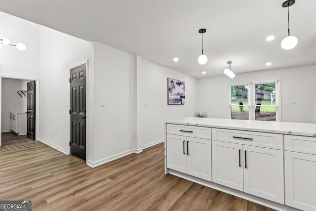 kitchen with light wood-style floors, hanging light fixtures, and white cabinetry