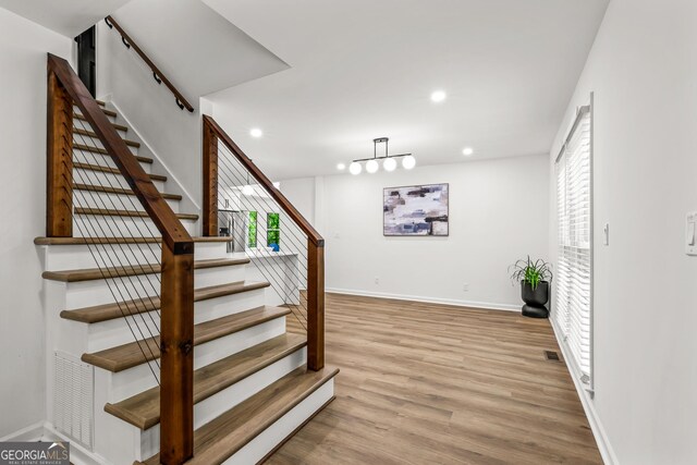 staircase with baseboards, wood finished floors, and recessed lighting