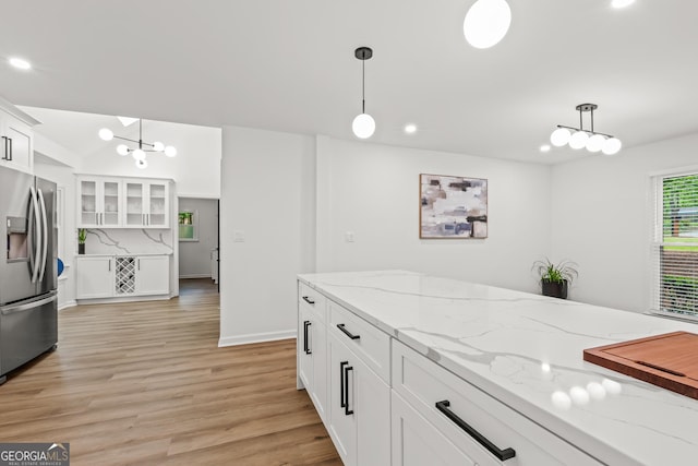 kitchen featuring white cabinets, stainless steel fridge with ice dispenser, light wood-type flooring, glass insert cabinets, and hanging light fixtures