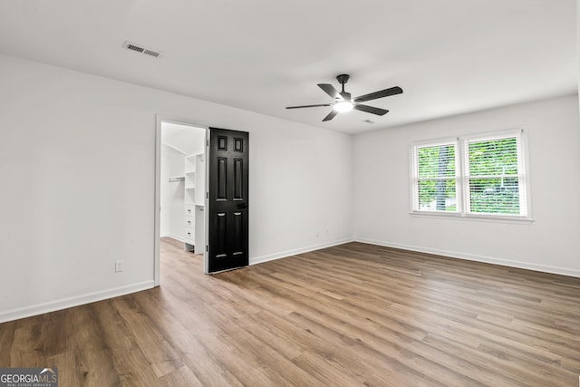 unfurnished room with wood finished floors, baseboards, a ceiling fan, and visible vents
