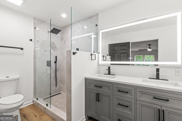 bathroom with toilet, wood finished floors, a sink, and a stall shower
