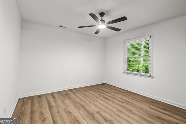 spare room with baseboards, wood finished floors, visible vents, and ceiling fan