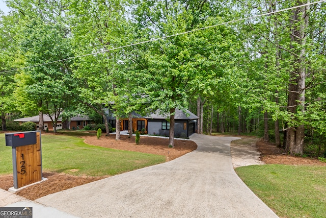 view of front of property featuring concrete driveway and a front lawn