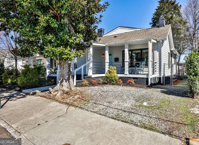 view of front of home with a gate, covered porch, a shingled roof, a chimney, and crawl space