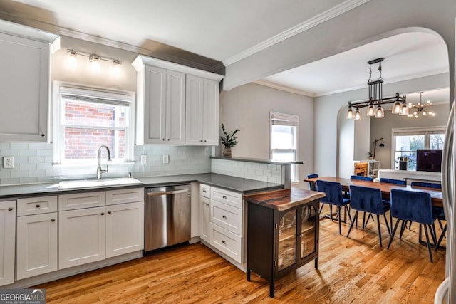 kitchen with a sink, dark countertops, dishwasher, and a peninsula