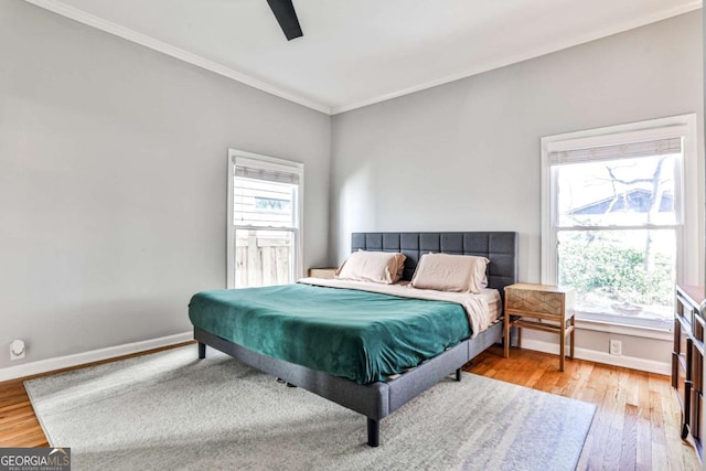 bedroom with baseboards, multiple windows, and light wood-style flooring