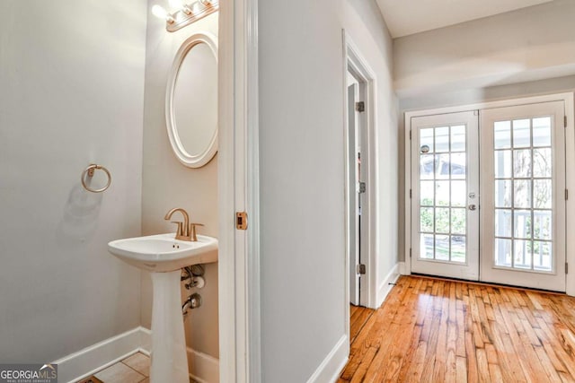 bathroom featuring french doors, baseboards, and wood-type flooring