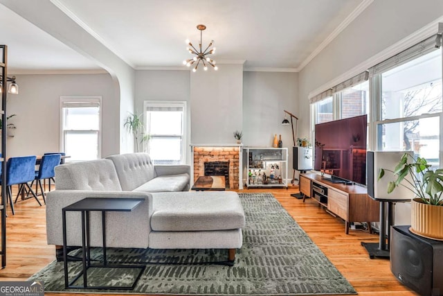 living room featuring a fireplace, arched walkways, light wood finished floors, and ornamental molding