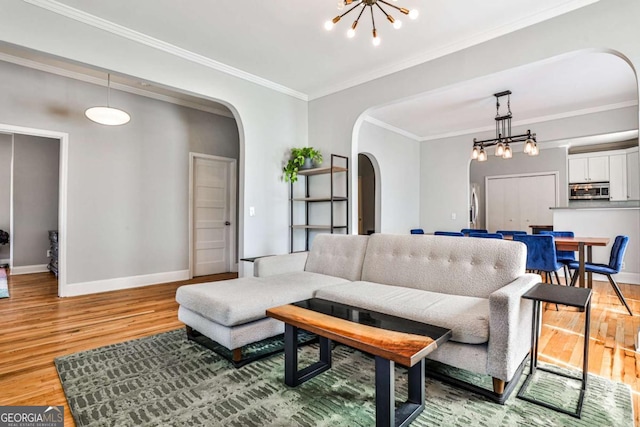 living room featuring ornamental molding, baseboards, arched walkways, and light wood-type flooring