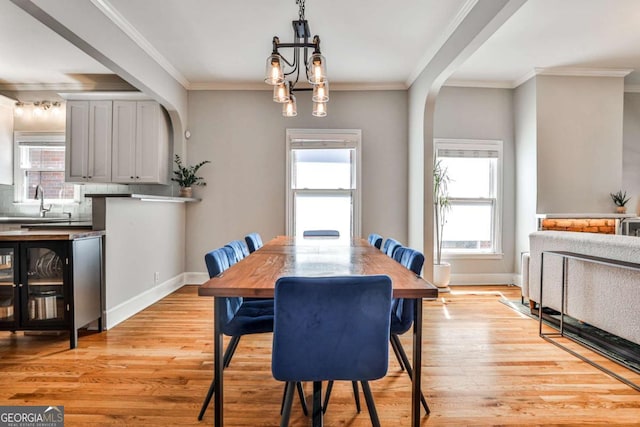 dining space with a healthy amount of sunlight, arched walkways, and light wood-type flooring