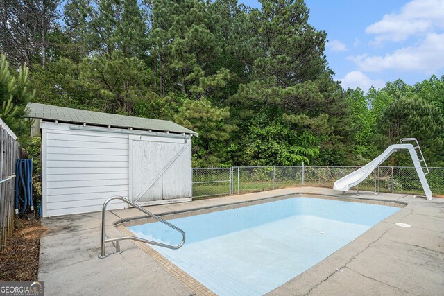410 Bowen Rd NE, White, GA 30184 - view of swimming pool featuring a storage shed, fence, a fenced in pool, an outdoor structure, and a water slide