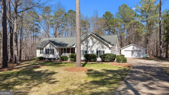 view of front facade featuring covered porch, a front yard, a detached garage, and an outdoor structure