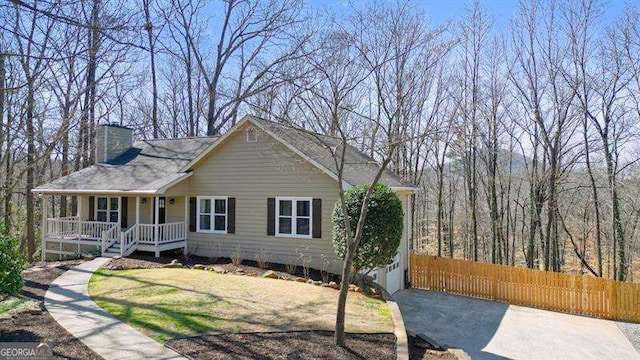 view of front of house with a porch, a chimney, a front lawn, and fence