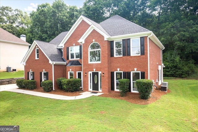 colonial home featuring brick siding, central AC unit, and a front yard