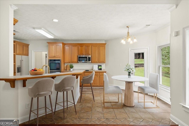 kitchen with a breakfast bar, light countertops, white refrigerator with ice dispenser, a textured ceiling, and stainless steel microwave