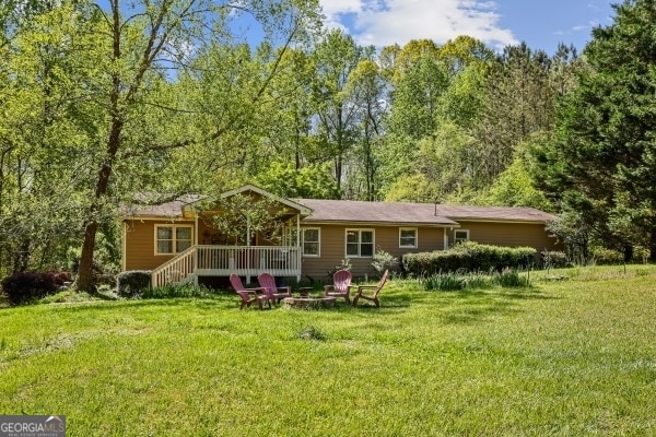 back of house with a fire pit and a yard