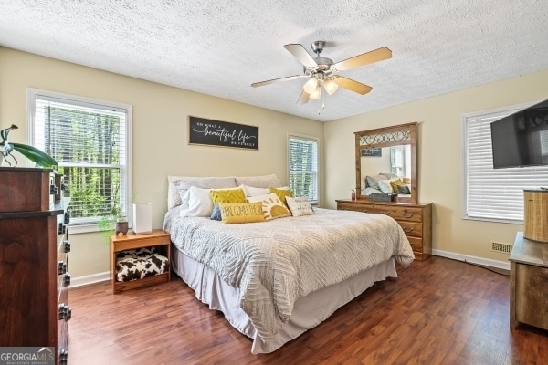 bedroom with dark wood-type flooring, a textured ceiling, and baseboards