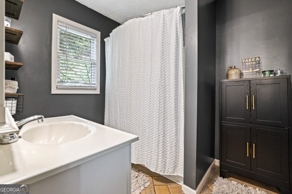 bathroom with curtained shower, vanity, and baseboards