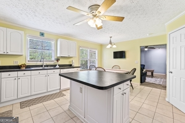 kitchen with dark countertops, ceiling fan with notable chandelier, and a sink