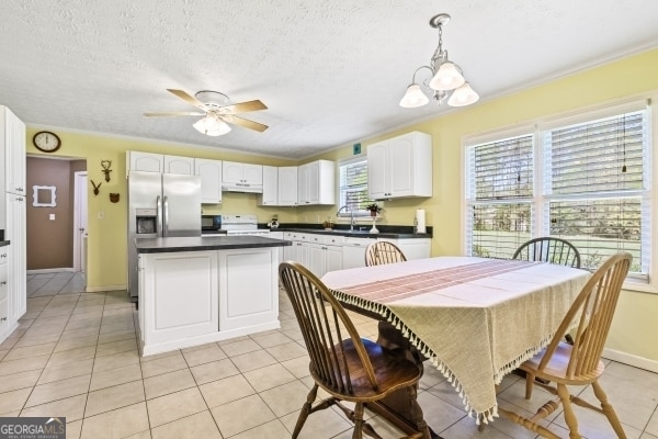 dining space with baseboards, light tile patterned floors, a textured ceiling, a ceiling fan, and crown molding