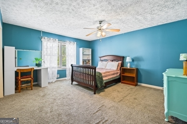carpeted bedroom with a textured ceiling, baseboards, and ceiling fan