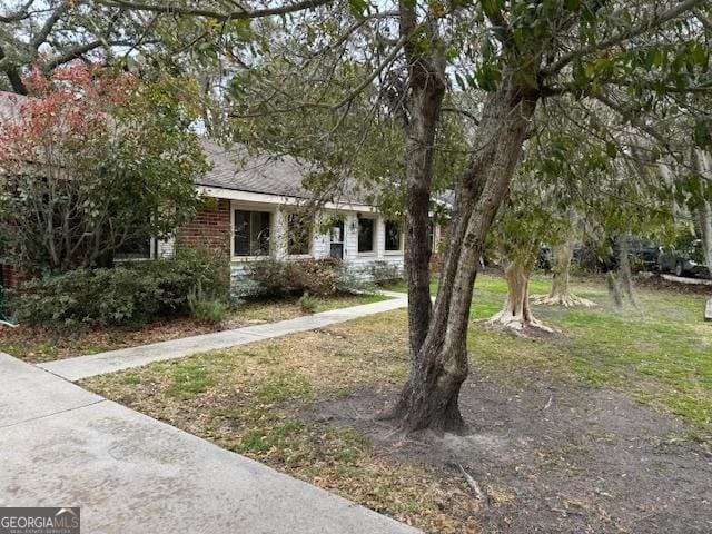 obstructed view of property with brick siding and a front yard