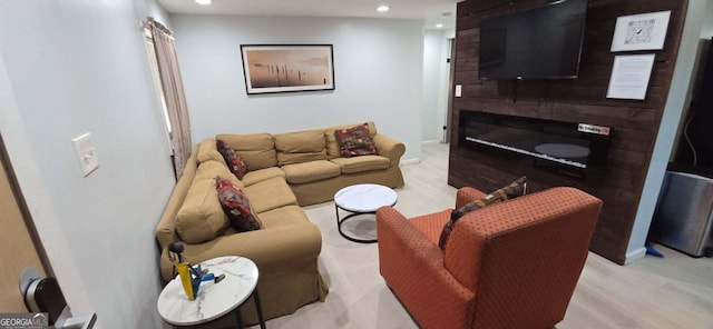 living room with a glass covered fireplace, recessed lighting, baseboards, and light wood-style floors