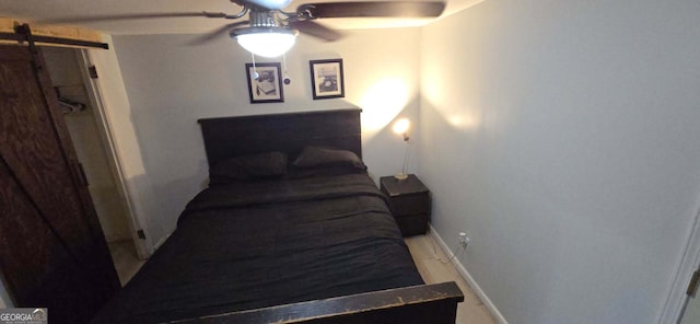 bedroom with a barn door, baseboards, and ceiling fan