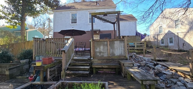 rear view of property with brick siding, a deck, and fence