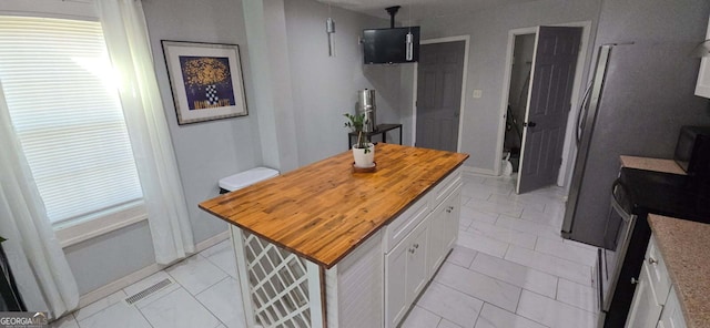 kitchen with stainless steel electric range oven, visible vents, wooden counters, a kitchen island, and white cabinets