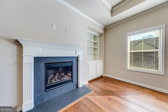 unfurnished living room with built in features, baseboards, a fireplace with flush hearth, ornamental molding, and hardwood / wood-style flooring