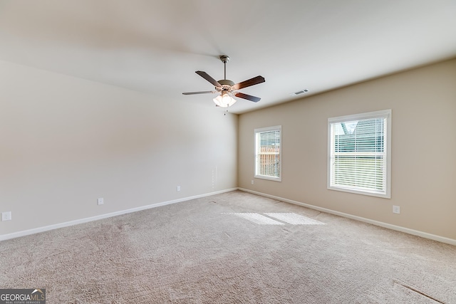 spare room with visible vents, light colored carpet, a ceiling fan, and baseboards