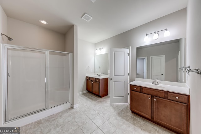 full bath with a shower stall, two vanities, visible vents, and a sink