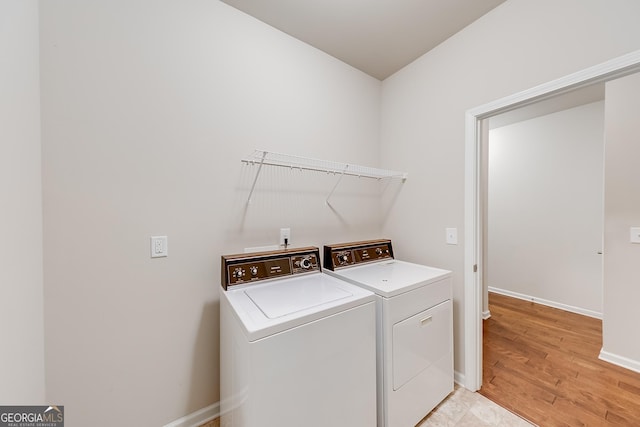 laundry area featuring laundry area, separate washer and dryer, baseboards, and light wood finished floors