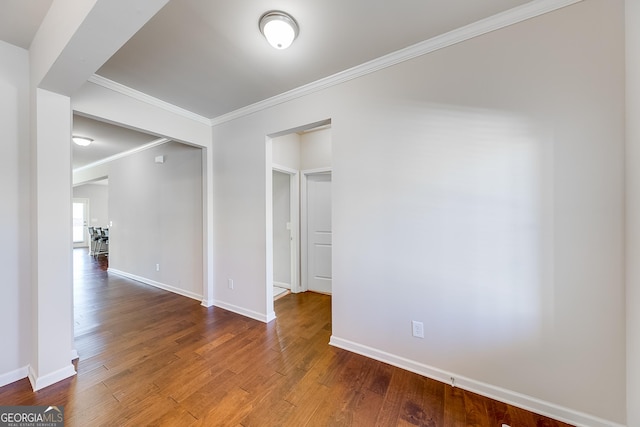 spare room with crown molding, wood finished floors, and baseboards