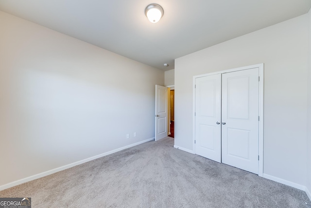 unfurnished bedroom featuring a closet, baseboards, and carpet flooring