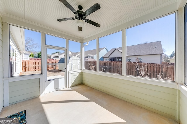 sunroom featuring a ceiling fan and a residential view