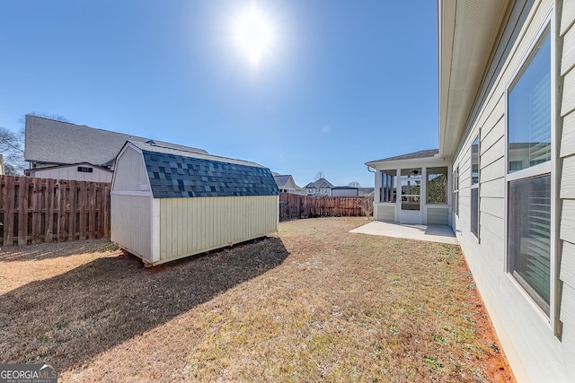 view of yard featuring an outdoor structure, a storage shed, a fenced backyard, and a patio area