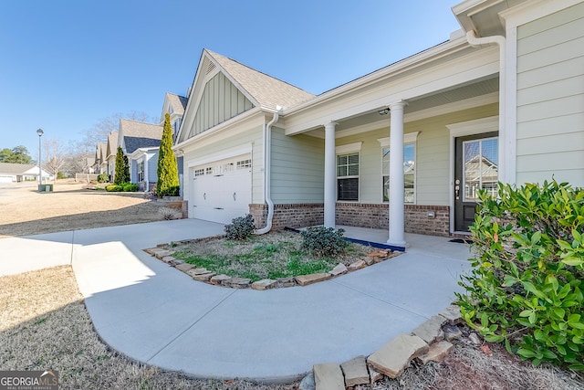 view of side of property featuring a porch, brick siding, board and batten siding, and driveway