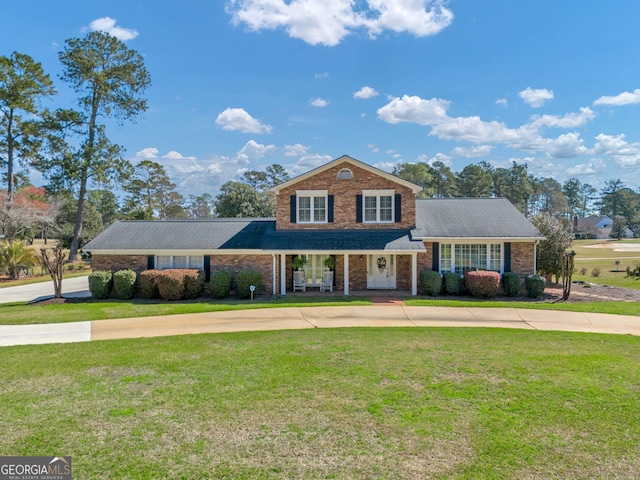 traditional-style house with a front lawn, concrete driveway, and brick siding